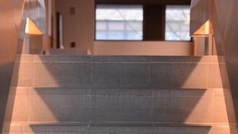 A stairway leading upward, illuminated by a bright light at the top, creating a warm and inviting atmosphere.
